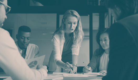 women pointing out data on a table in front of a team